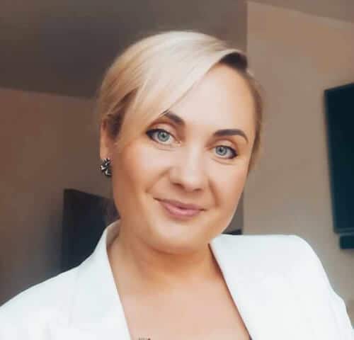 Smiling woman with blonde hair in professional setting, representing business and leadership.