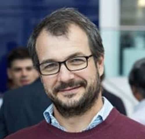 Friendly professional man with glasses smiling at a corporate event.