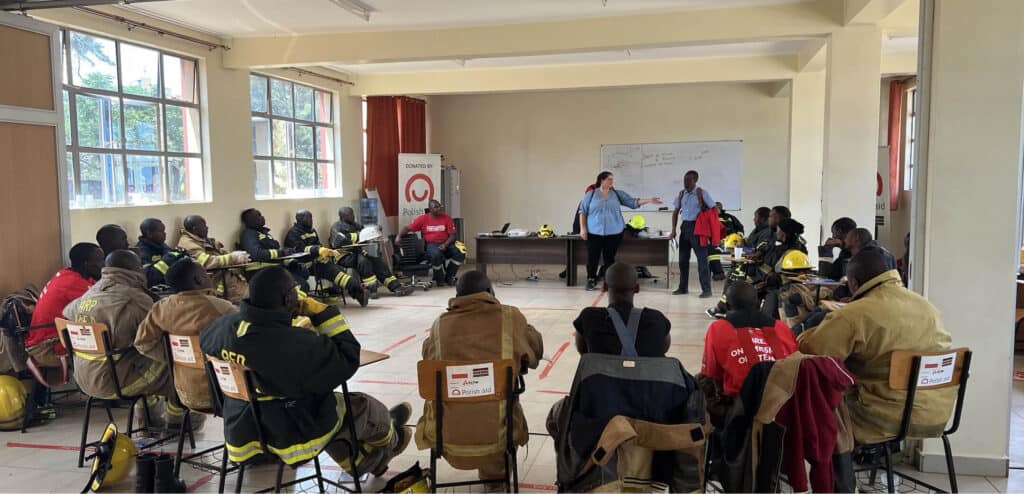 Emergency firefighter training session indoors with trainees in uniform and instructors teaching.