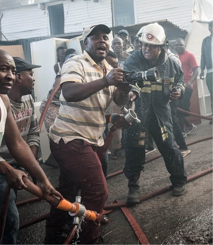 Firefighters and rescue workers battling a fire in a crowded area.