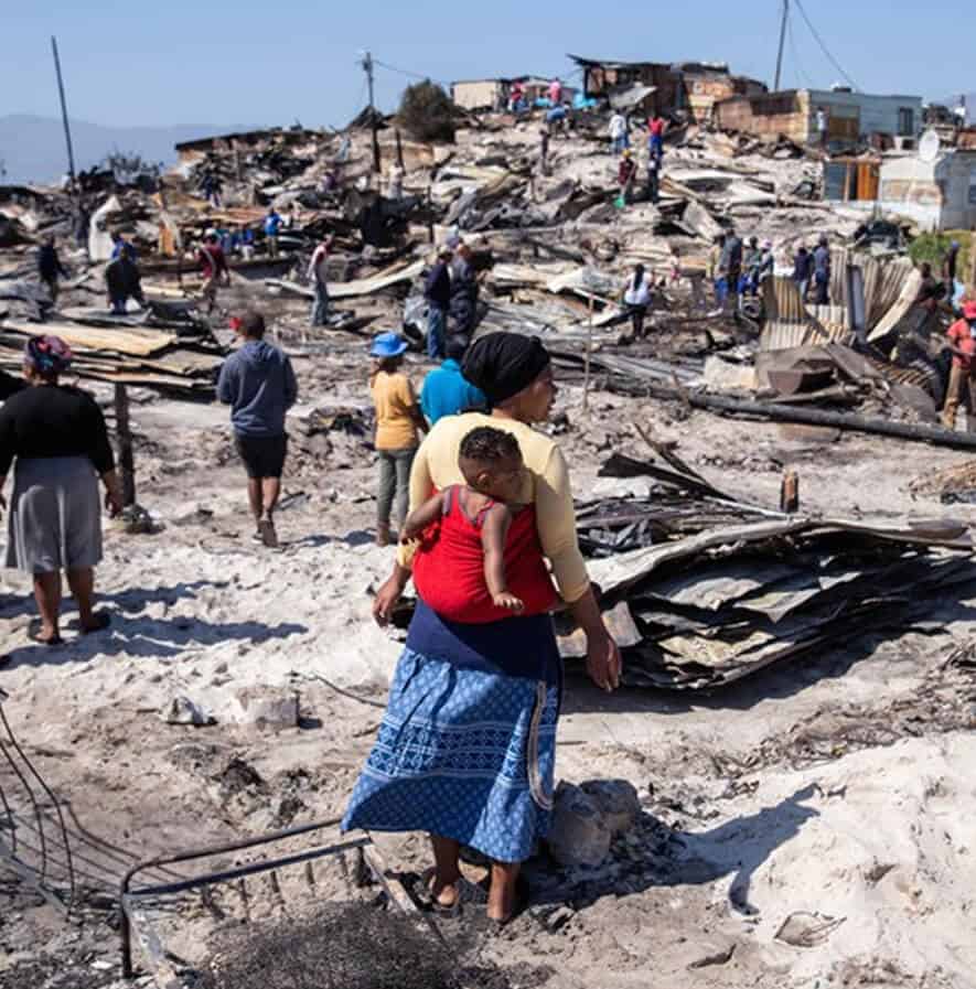 Collapsed building after disaster, people inspecting aftermath, rescue and relief efforts in affected area.
