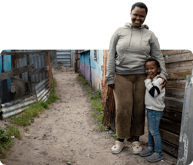 A young woman and child smiling in a poverty-stricken neighborhood.